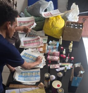 Petugas Polsek Pakuhaji memperlihatkan barang bukti uang palsu senilai Rp68,57 juta beserta peralatan produksi yang disita dalam pengungkapan kasus di Tangerang.